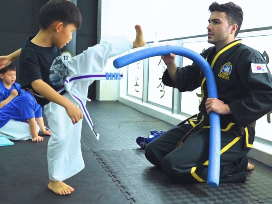 A young student practising a kick with an instructor at CHOICES Choi Kwang Do